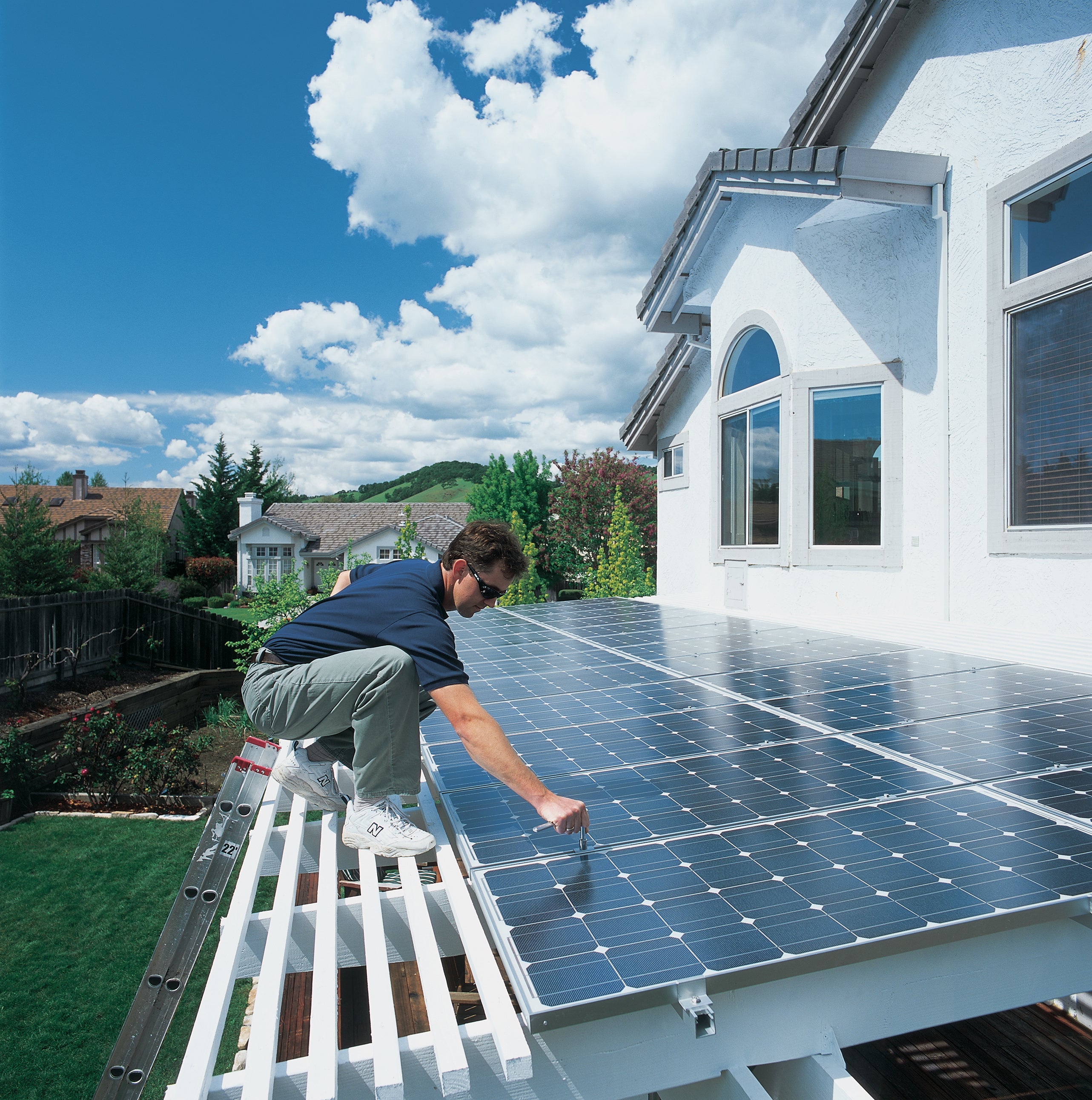 A man installs rooftop solar panels on a roof.